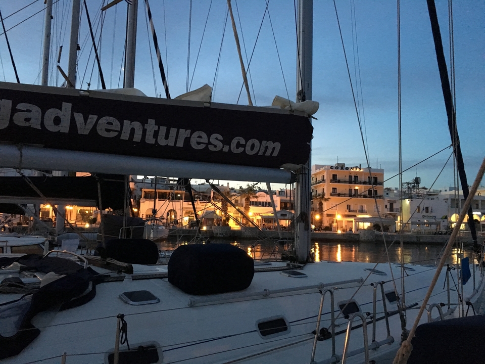 Un voilier amarré avec des lumières nocturnes se reflétant dans l'eau.