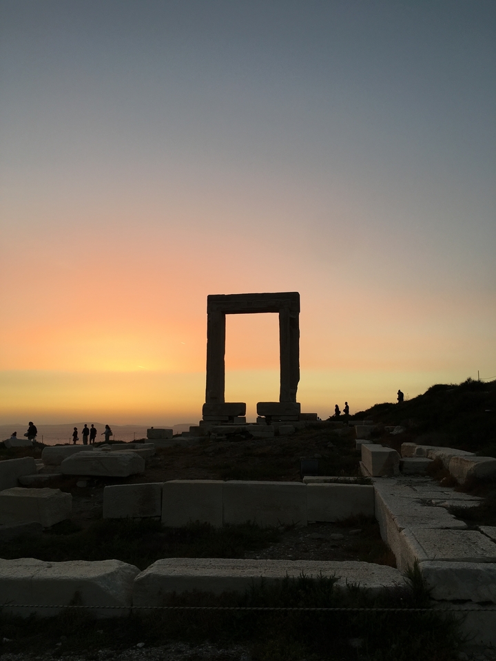 Ancienne structure de pierre silhouettée contre un coucher de soleil coloré.