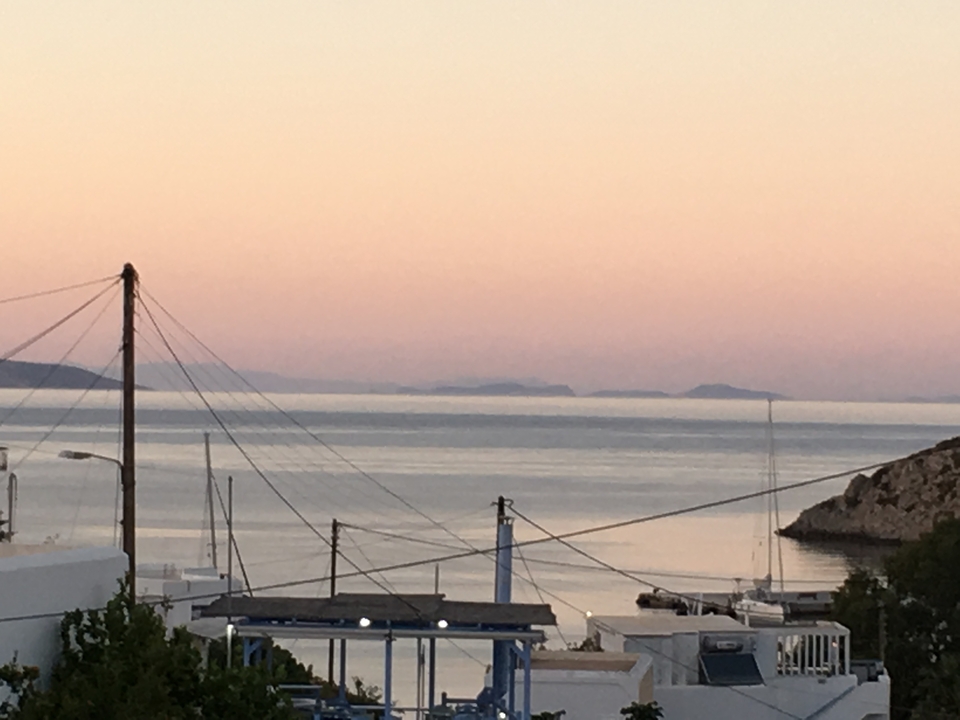 Mer calme avec des îles lointaines sous un ciel rosâtre.