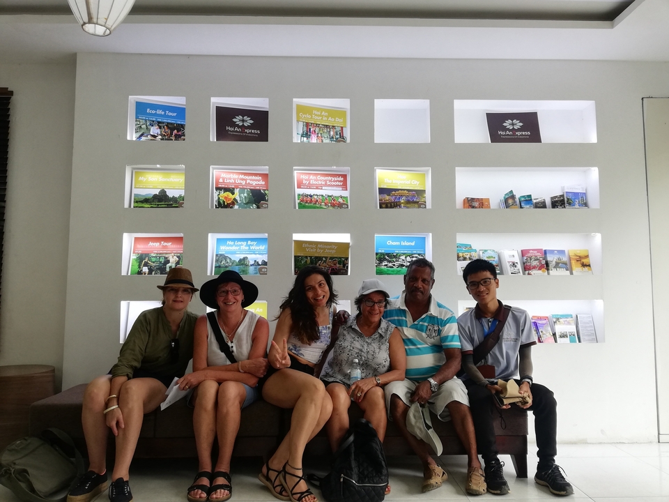 Groupe de personnes assises sur un canapé avec des brochures de voyage en arrière-plan.