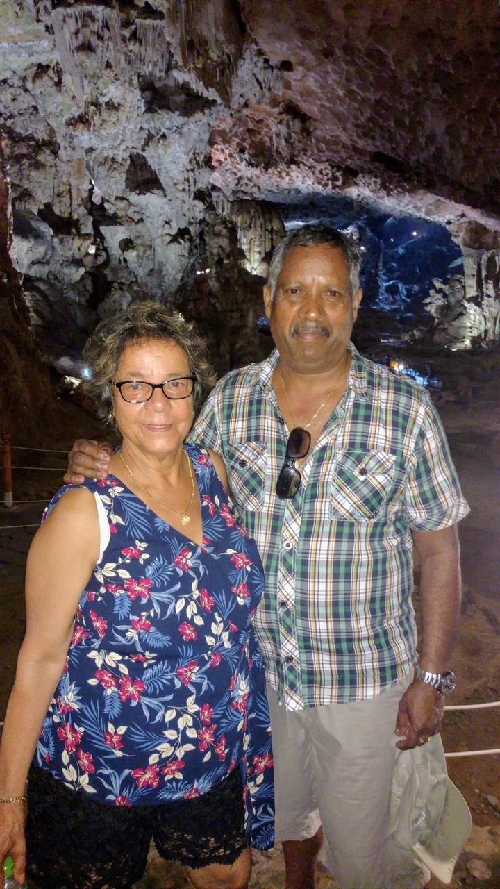 Deux personnes souriantes à l'intérieur d'une grotte ou d'un intérieur sombre.