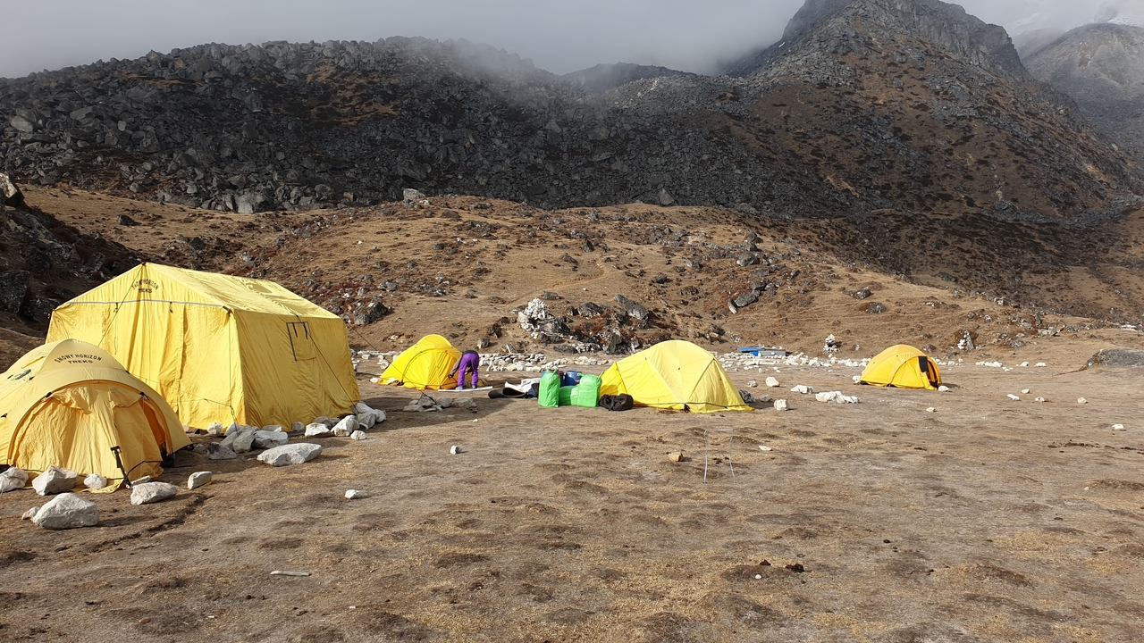 Des tentes jaunes installées dans une zone de camp de base en montagne.