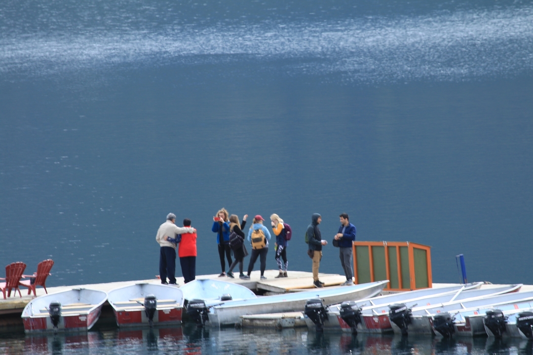 Groupe de personnes debout sur un quai au bord de l'eau.