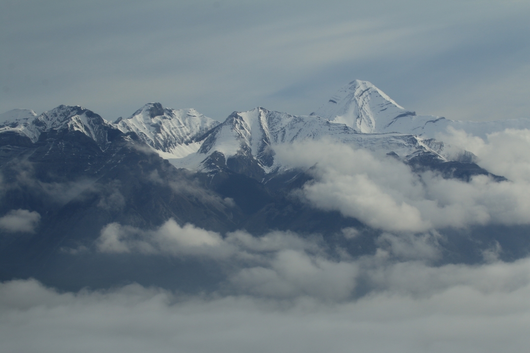 Montagnes enneigées avec des nuages en dessous des sommets.