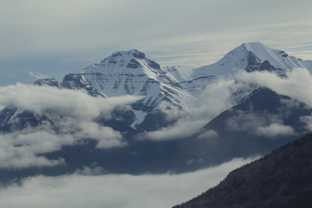 Sommets montagneux enneigés partiellement obscurcis par les nuages.