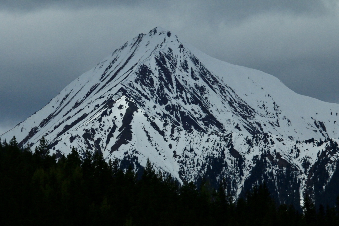 Un sommet de montagne enneigé sous un ciel nuageux.