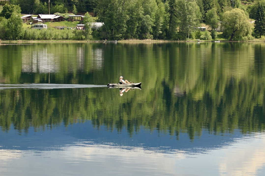 Personne faisant du kayak sur un lac serein avec un environnement luxuriant.