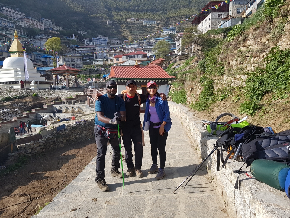 Trois randonneurs posant avec une ville en arrière-plan.