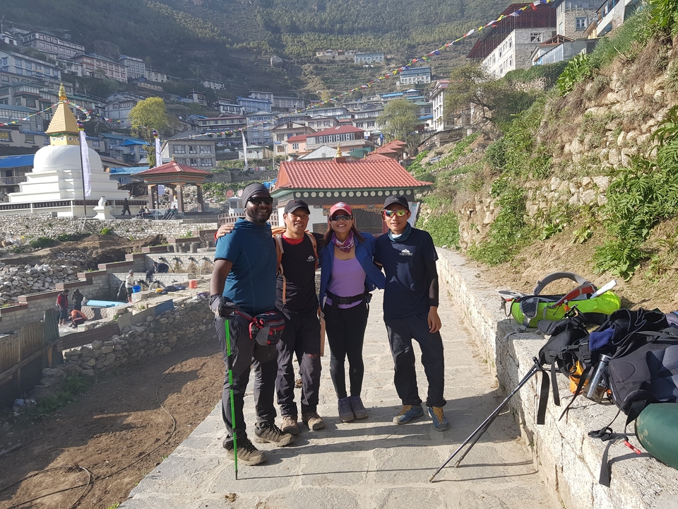 Quatre randonneurs posant ensemble avec une ville en arrière-plan.