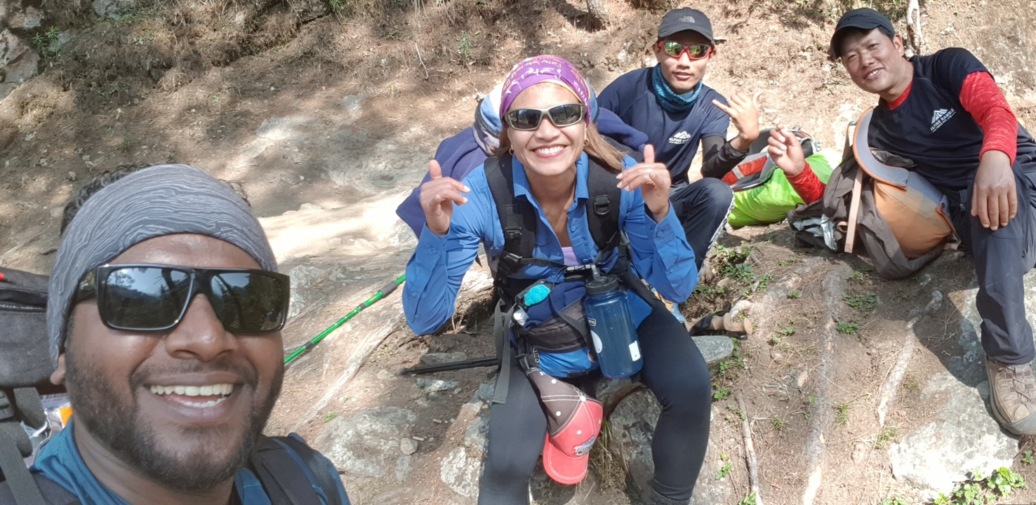 Quatre randonneurs assis sur une surface rocheuse souriant à la caméra.