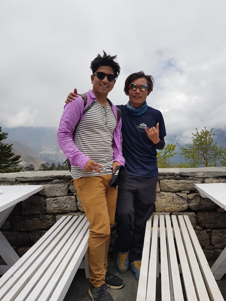 Deux hommes posant à l'extérieur avec des montagnes en arrière-plan.