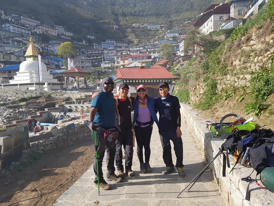 Quatre randonneurs posant ensemble avec une ville en arrière-plan.