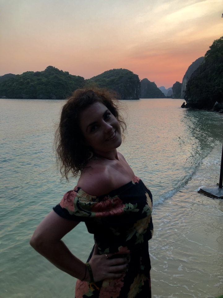 Woman smiling on a beach during sunset.