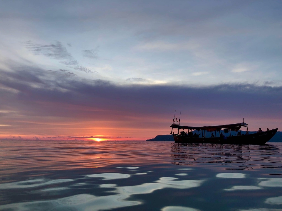 Boat on water with a vibrant sunset in the background.