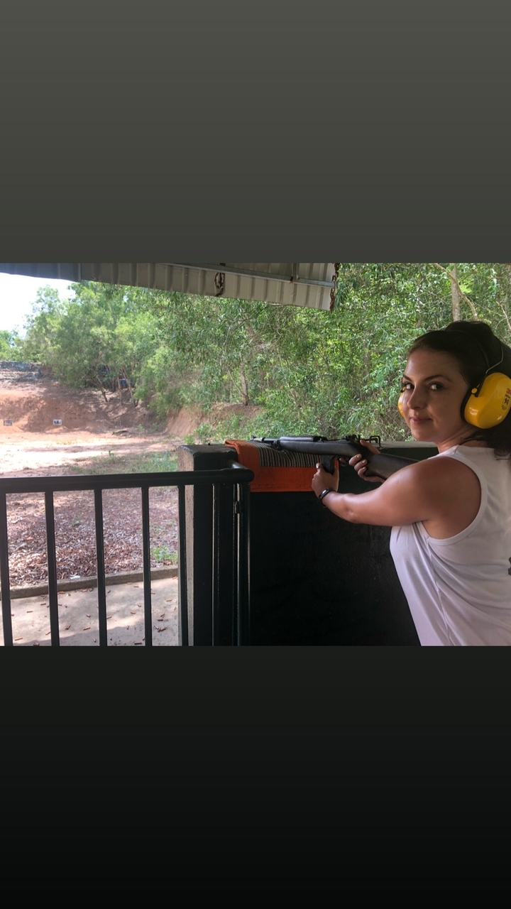 Femme tenant un pistolet dans un stand de tir.