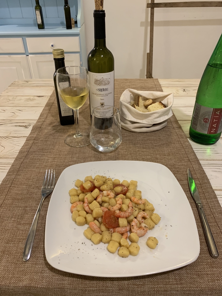 Dressage de table avec une assiette de gnocchis et de crevettes.