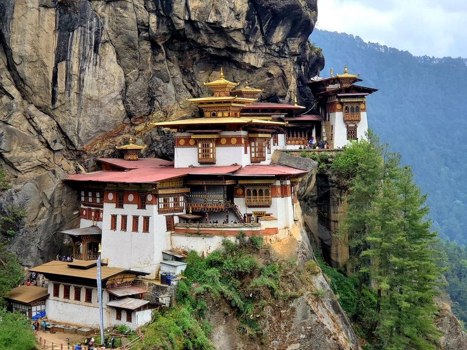 Monastère de Taktsang perché sur une falaise entouré d'une végétation luxuriante.