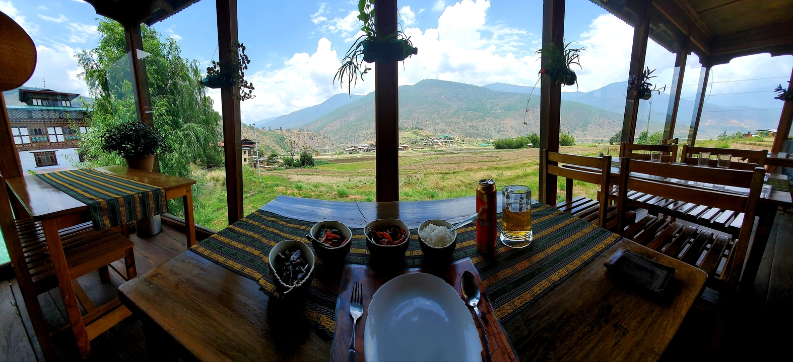 Vue intérieure d'un restaurant donnant sur une vallée pittoresque avec des montagnes.