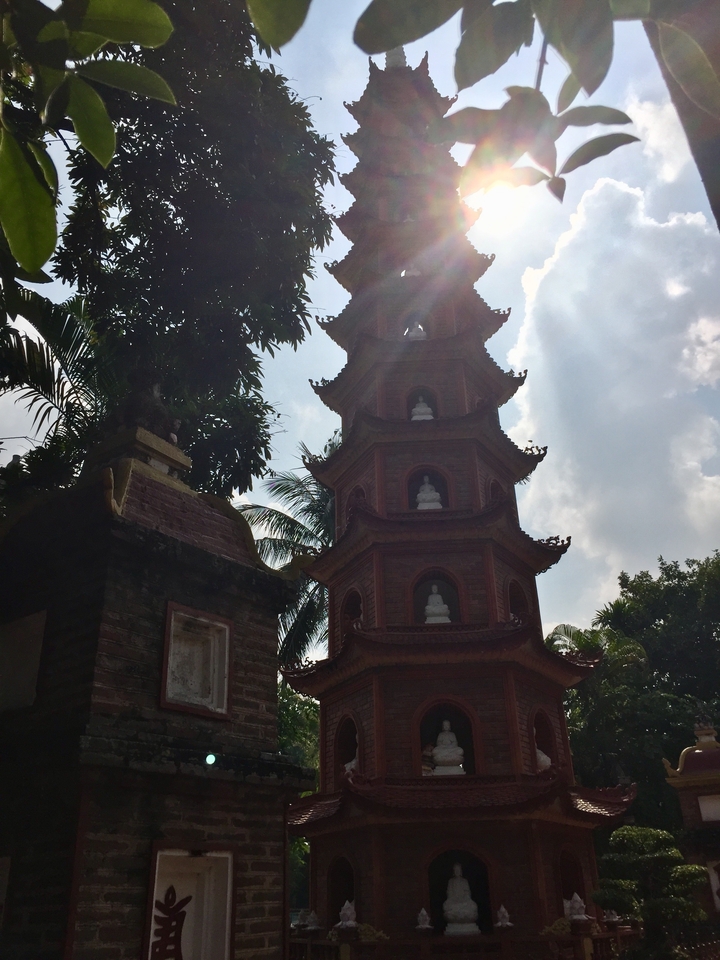 Pagode entourée de feuillage vert sous un ciel bleu.