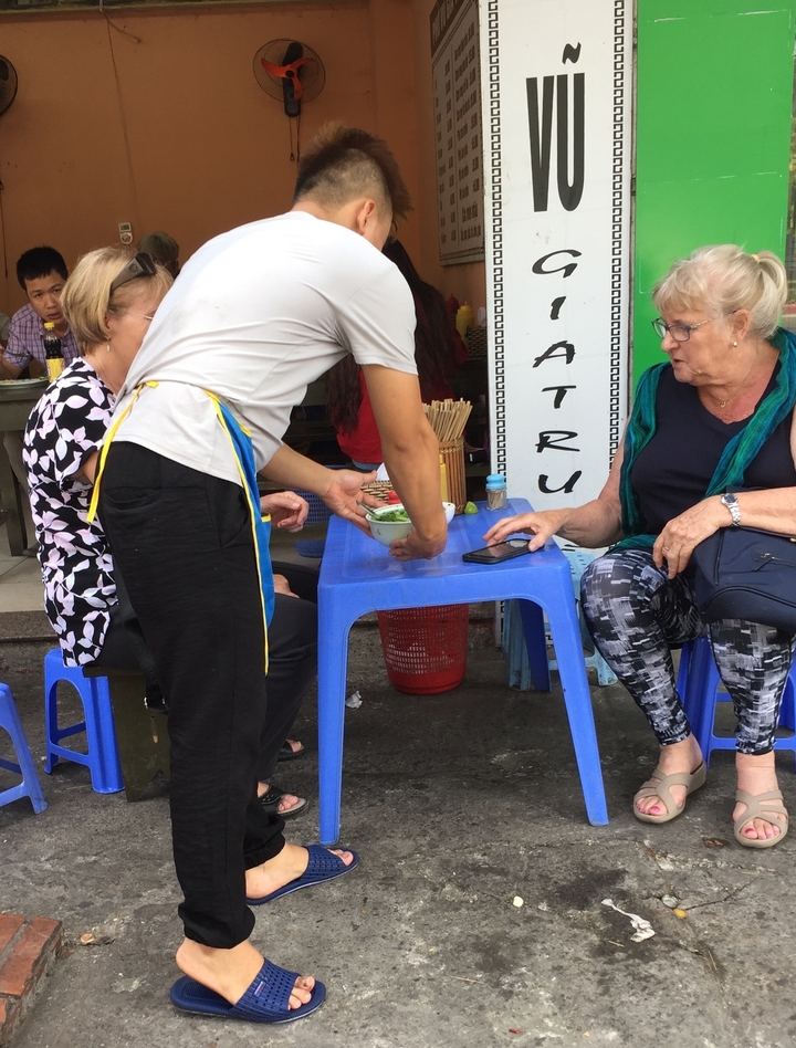 Femme servie à table sur le trottoir.