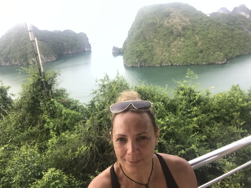 Femme posant avec une vue panoramique d'îles calcaires en arrière-plan.
