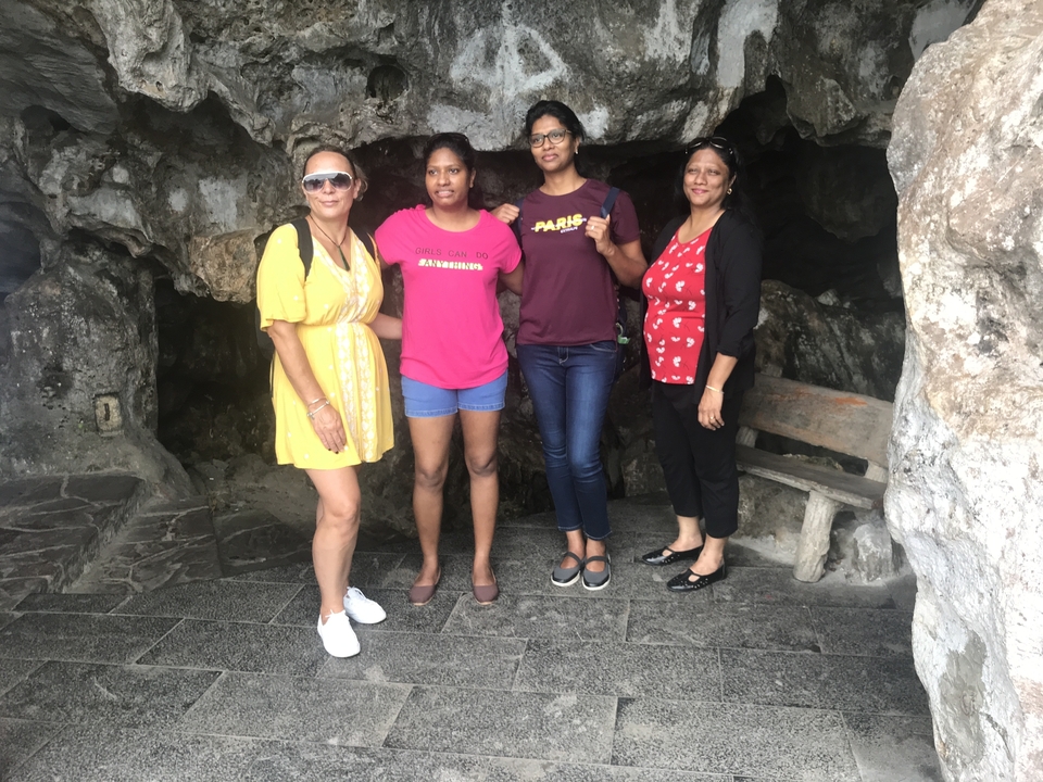 Quatre femmes debout à l'entrée d'une grotte, souriantes.