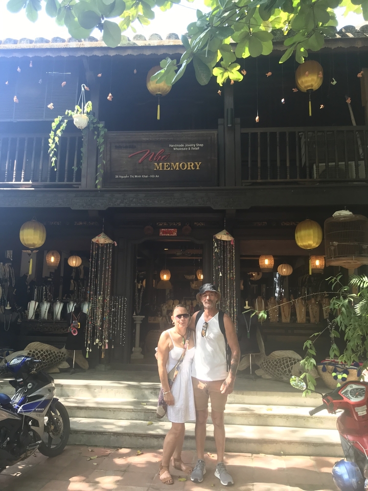 Deux personnes posant devant un bâtiment traditionnel avec des décorations.