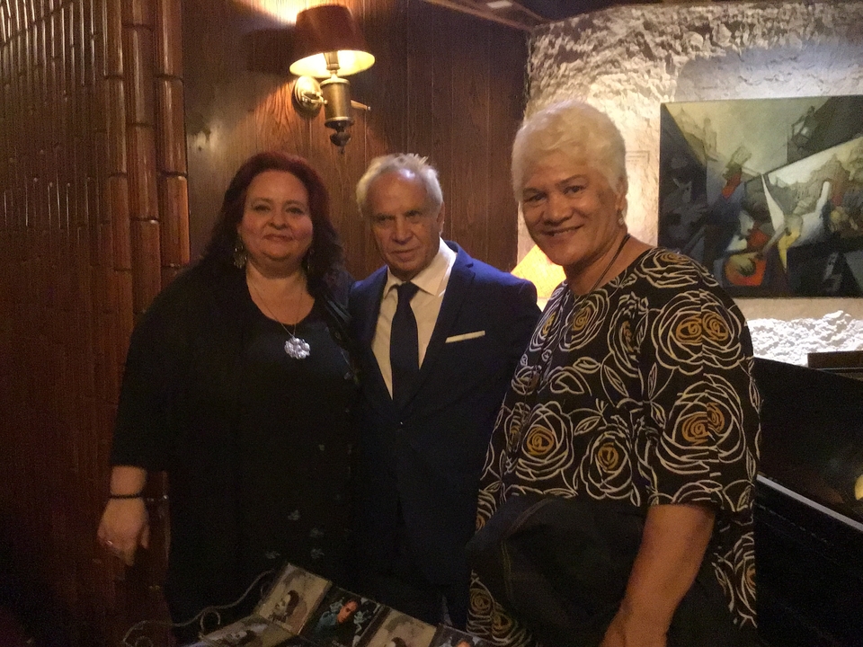 Trois personnes posent à l'intérieur.
