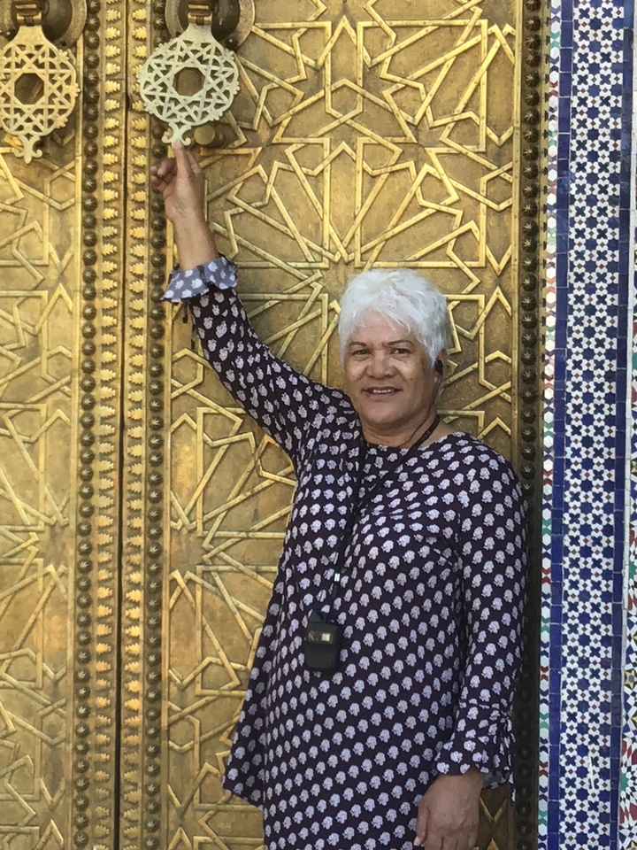 Personne debout devant une porte dorée complexe.