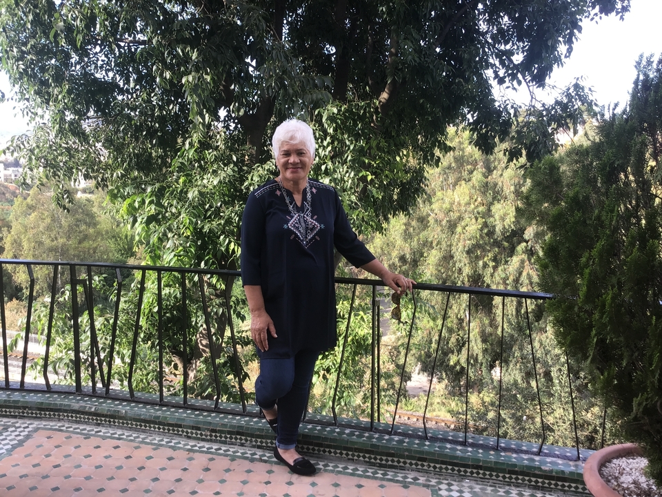 Personne posant près d'une rambarde métallique entourée de verdure.