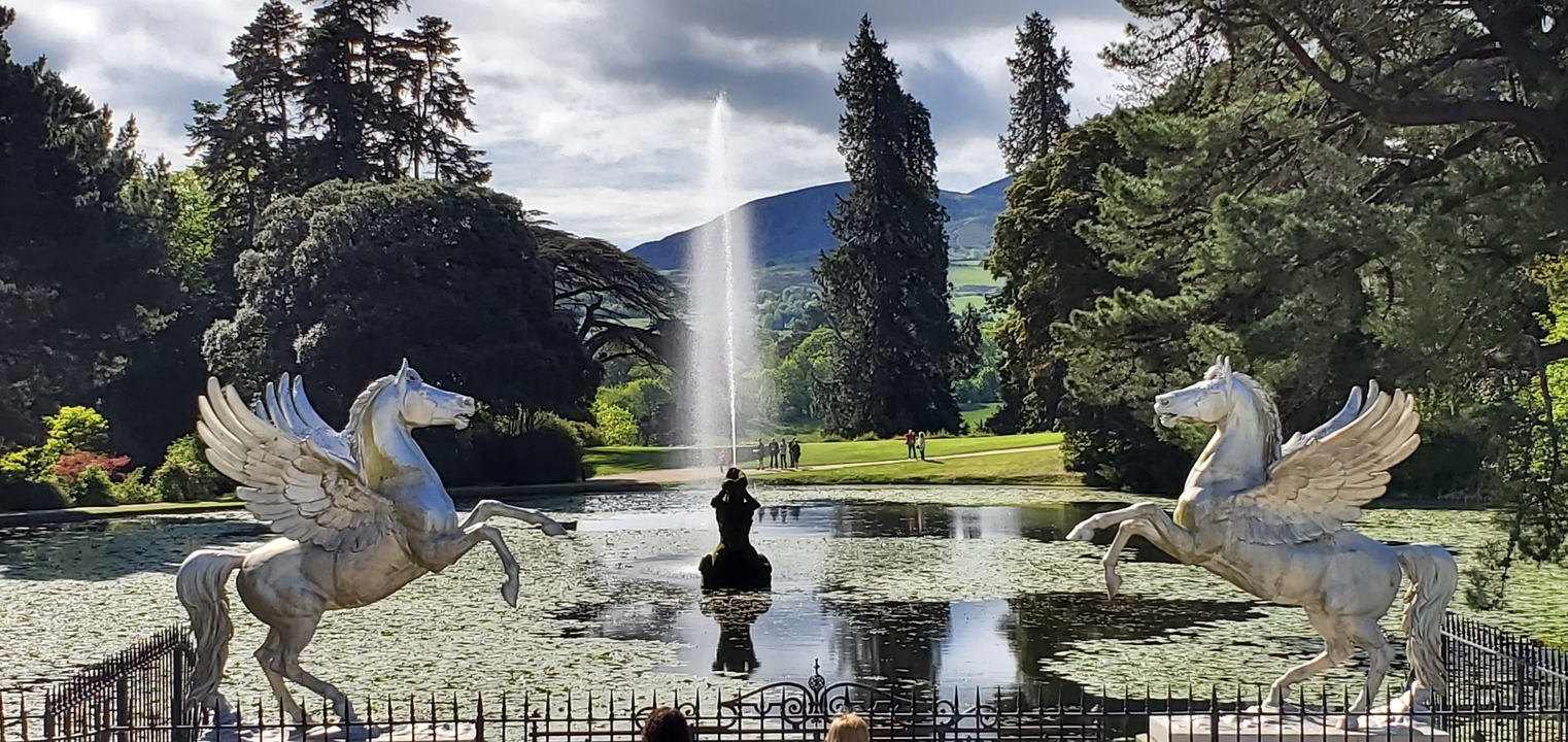 Fontaine avec sculptures de chevaux mythiques dans un cadre de jardin.