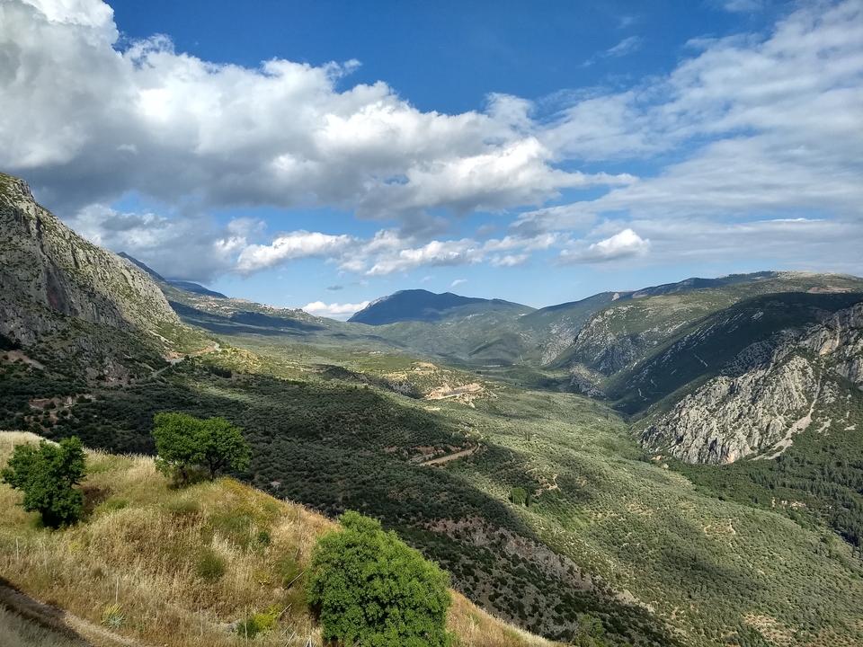 Une vue large d'une vallée avec des montagnes sous un ciel nuageux.