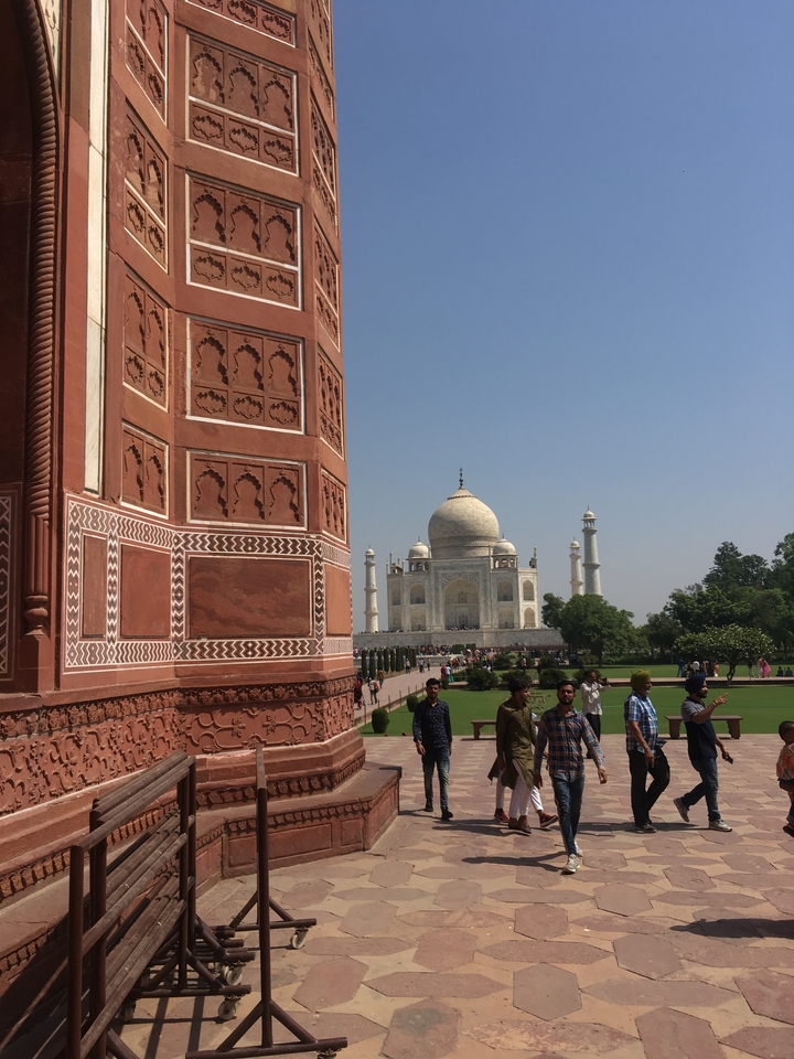 Le Taj Mahal vu de côté avec des visiteurs autour.