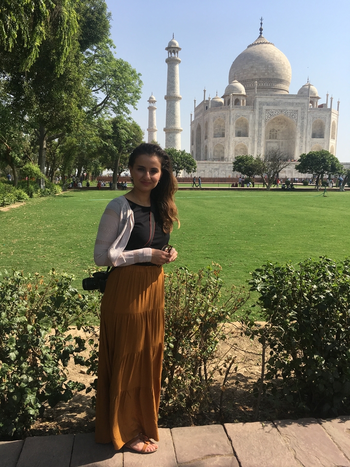 Personne debout dans un jardin, avec le Taj Mahal visible en arrière-plan.