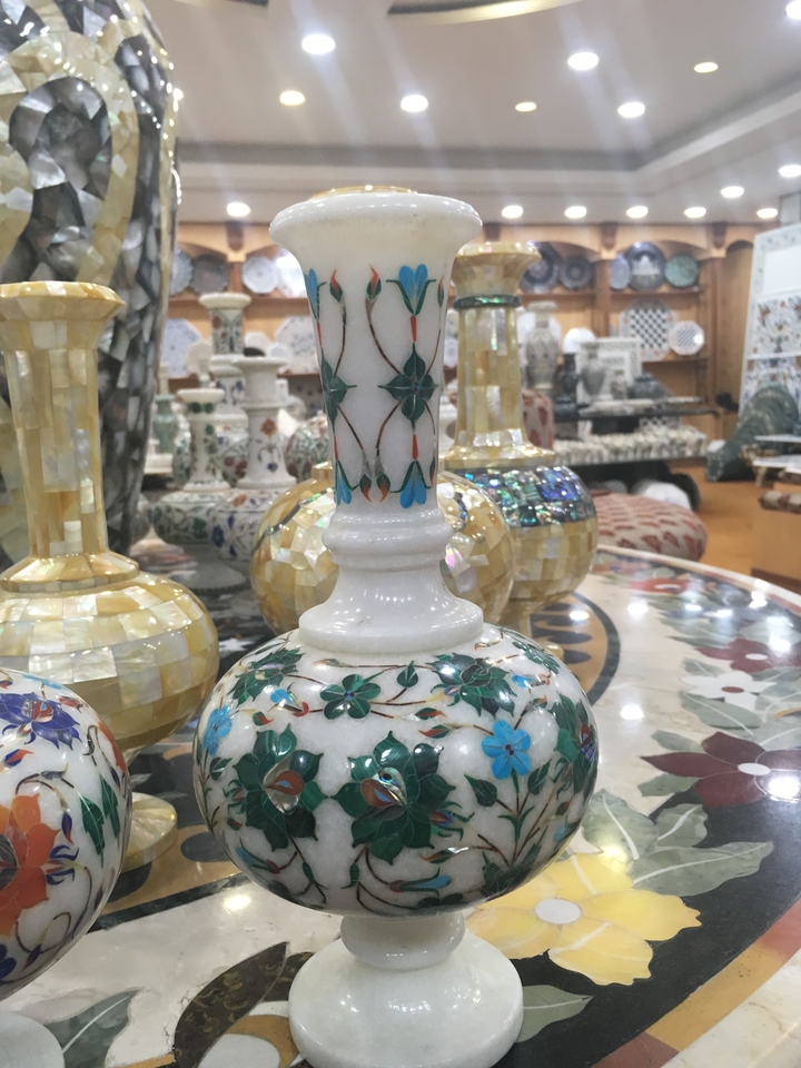 Vase en marbre avec des motifs décoratifs, exposé parmi d'autres objets.