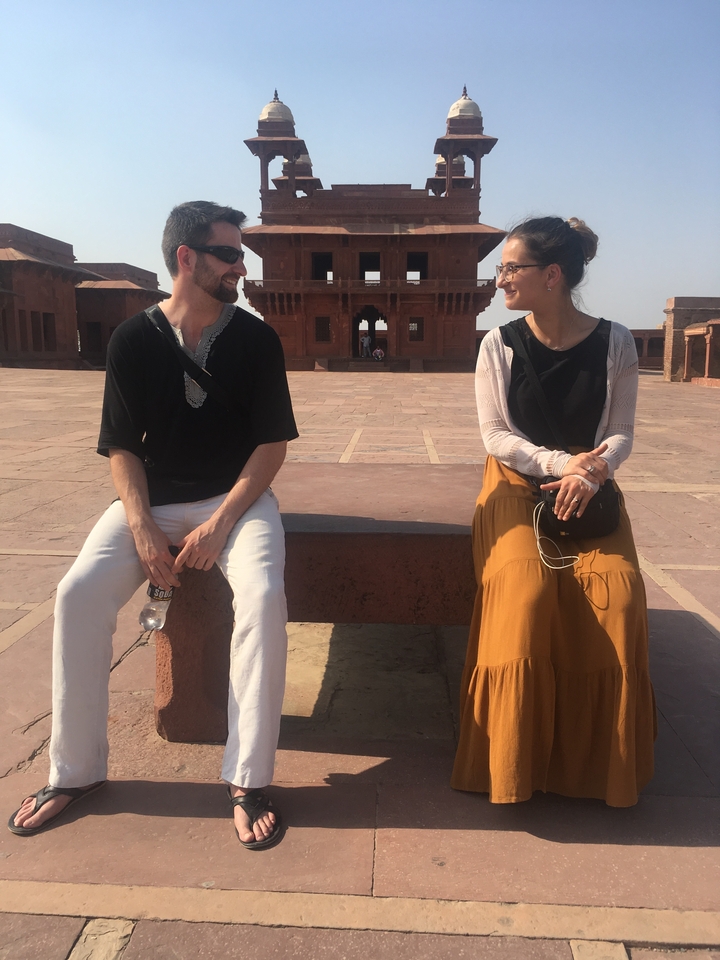 Deux personnes assises sur un banc de pierre dans un site historique.