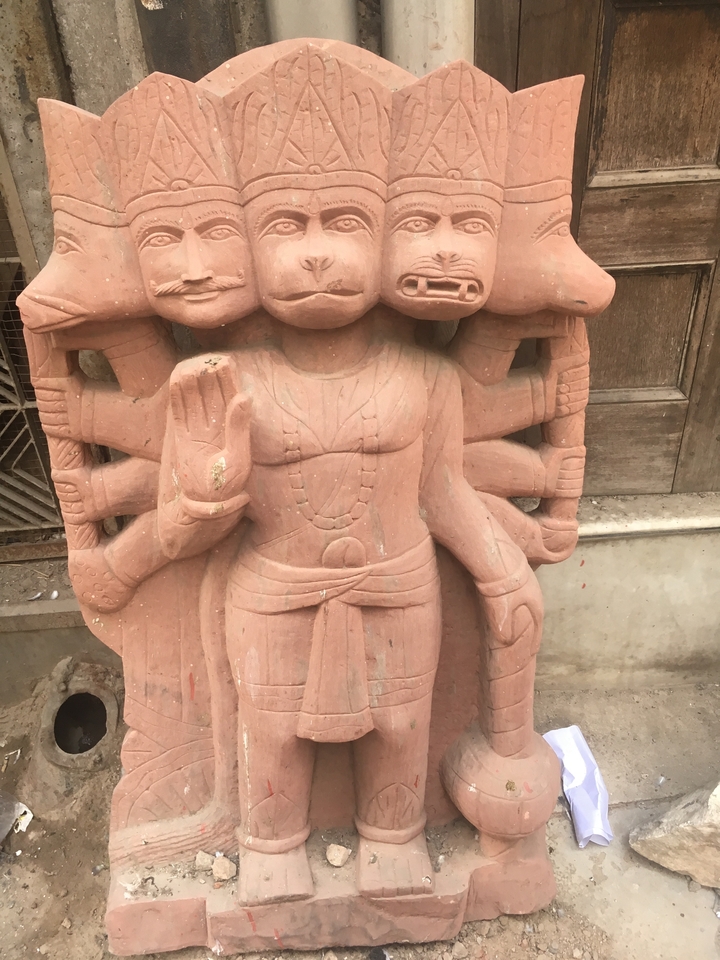 Une sculpture en pierre d'une figure à plusieurs têtes avec des détails complexes.