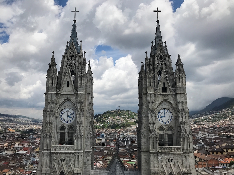 Vue d'une cathédrale gothique avec des tours jumelles et des cadrans d'horloge.