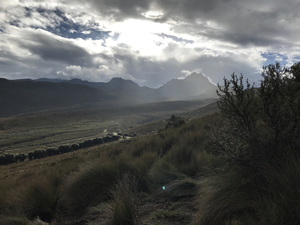 Paysage dramatique avec des montagnes escarpées et le soleil perçant à travers les nuages.