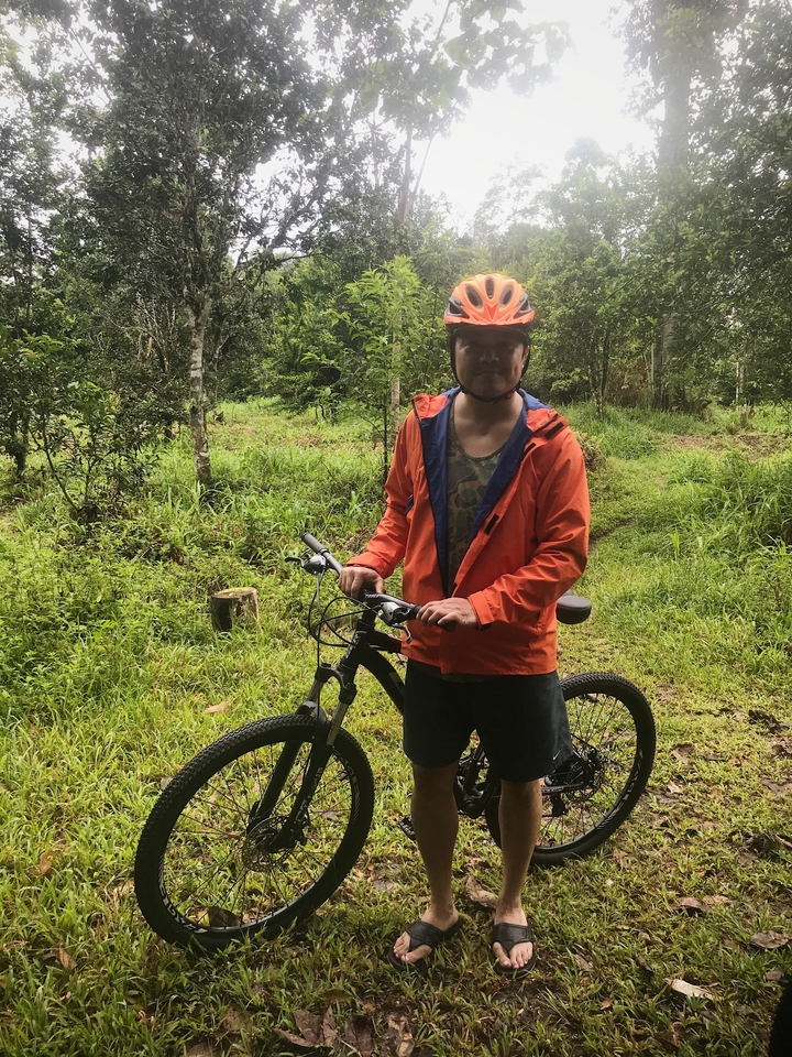Personne avec un vélo dans un cadre forestier portant un casque et une veste.