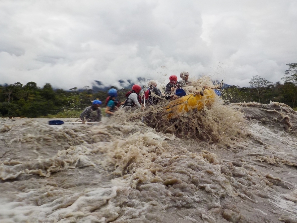 Groupe de personnes faisant du rafting dans des eaux turbulentes avec une forêt en arrière-plan.