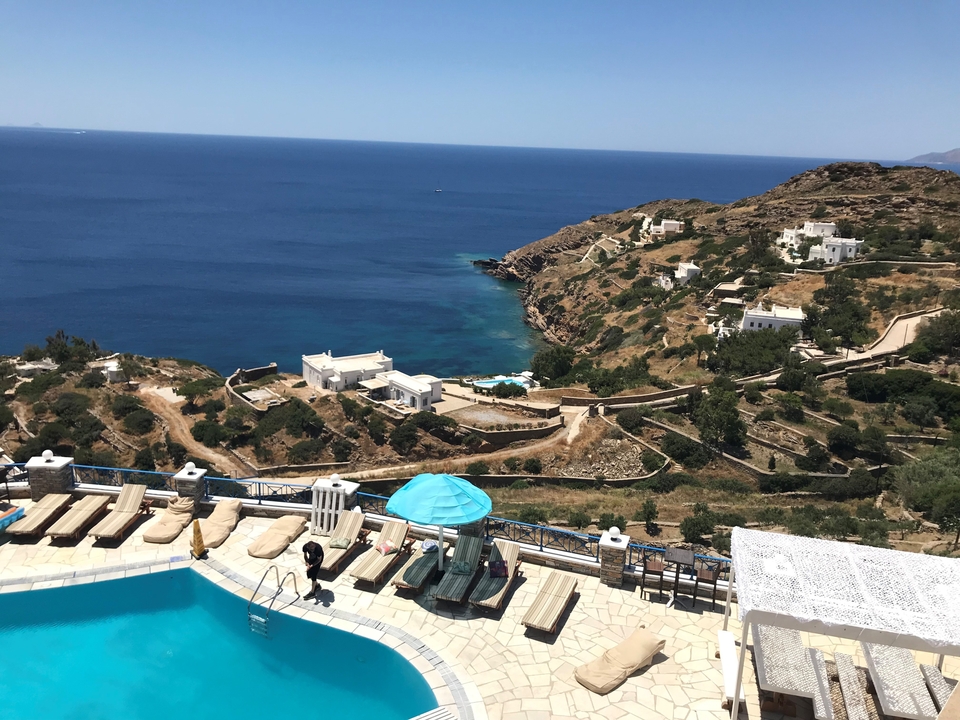 Vue côtière avec piscine et bâtiments blancs sur une colline.