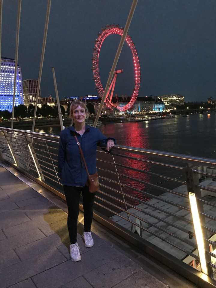Femme debout sur un pont avec le London Eye en arrière-plan.