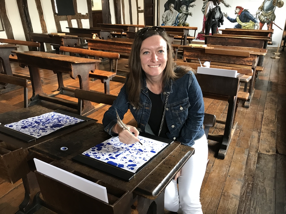 Femme assise dans une salle de classe historique avec des bureaux en bois.