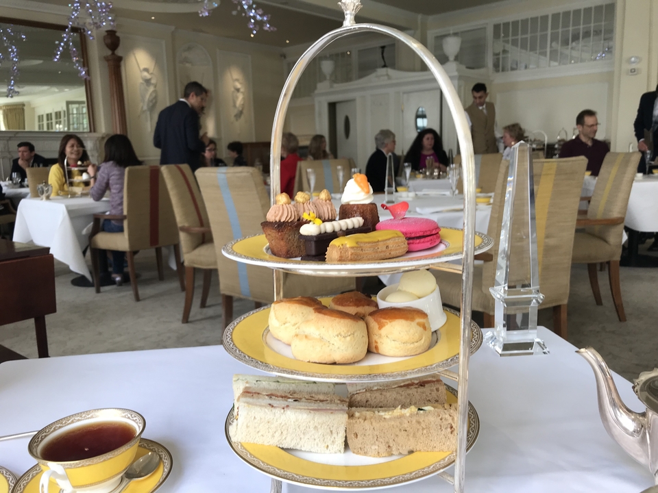 Configuration de thé de l'après-midi avec pâtisseries et personnes en arrière-plan.