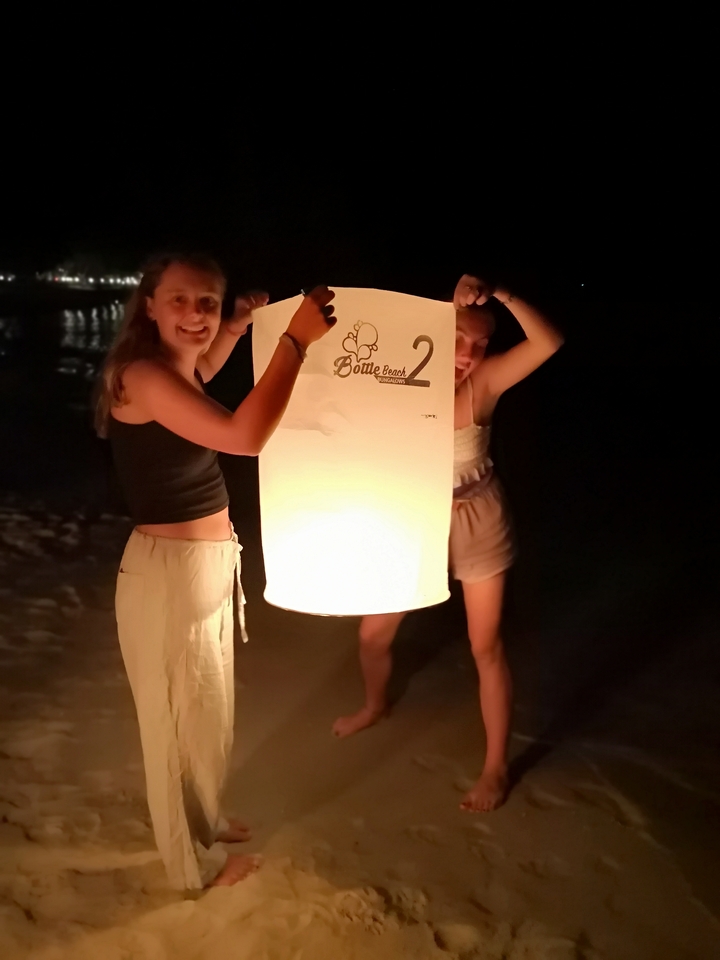 Des gens tenant une lanterne sur une plage la nuit.