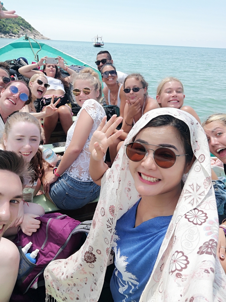 Group of people on a boat smiling and waving.