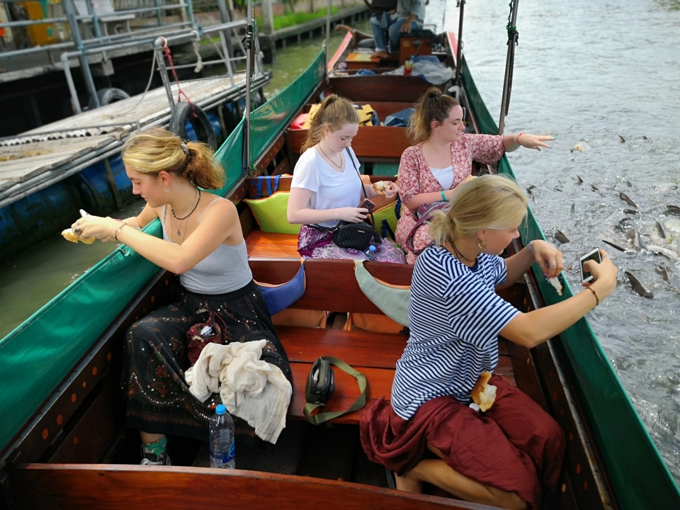 Des gens dans un bateau qui nourrissent ou observent des poissons dans l'eau.