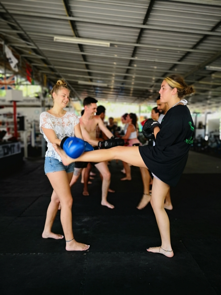 People practicing kickboxing or Muay Thai in a training facility.