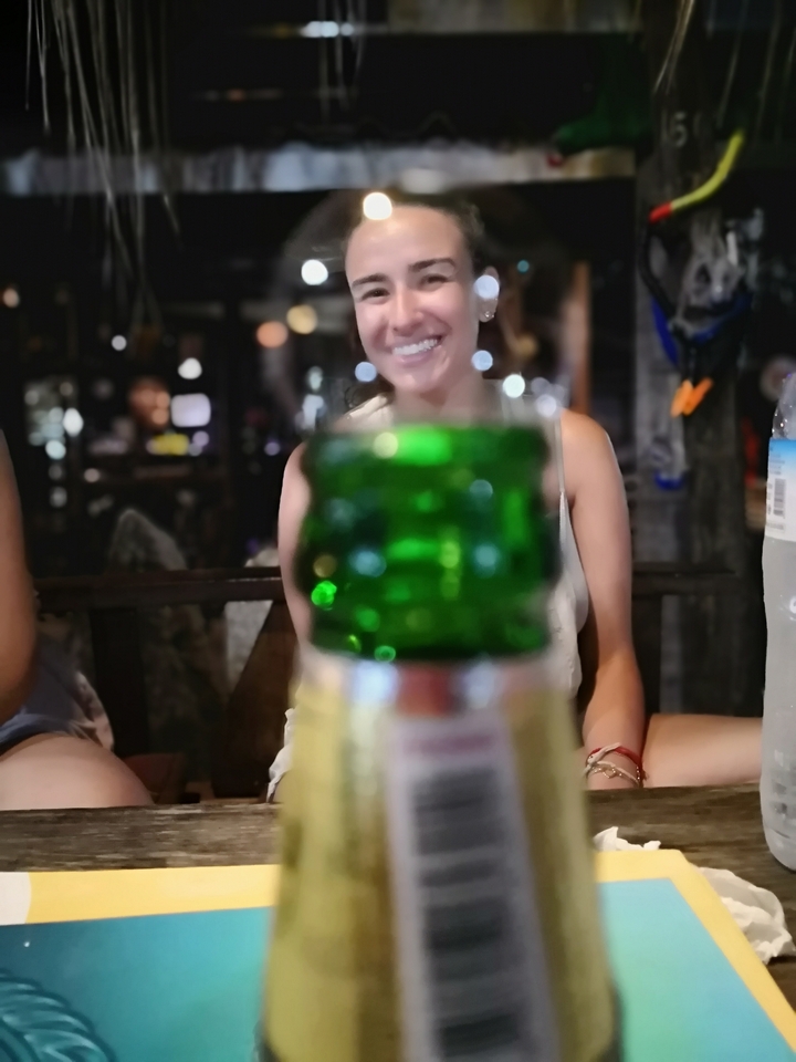 Image floue d'une personne derrière une bouteille verte.